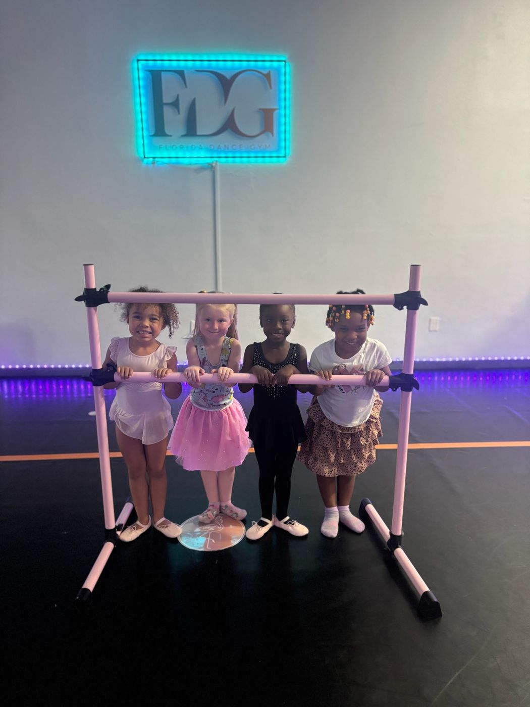 Young dancers smiling together at the barre inside Florida Dance Gym
